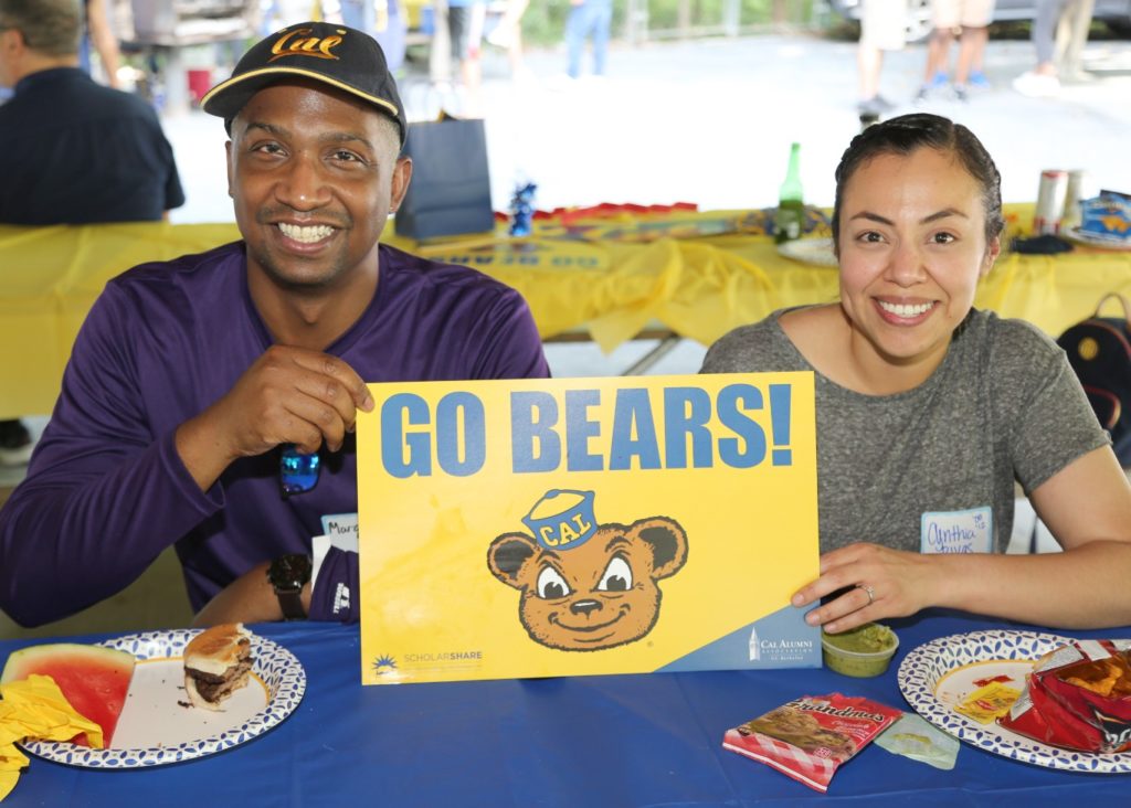 two alumni holding go bears sign